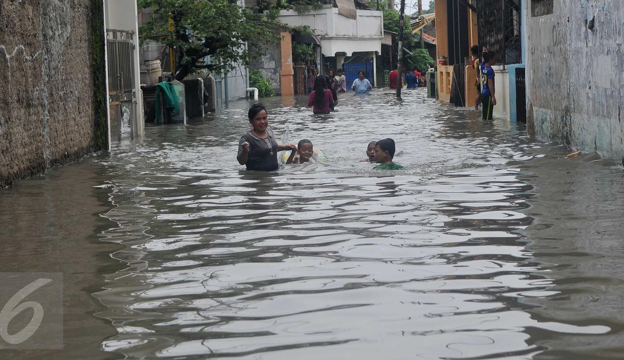 Warga menuntun anaknya melewati banjir yang mencapai pinggang orang dewasa di Rawa Buaya, Jakarta, Minggu (28/2/2016). Banjir terjadi akibat luapan Kali Mookervart yang diguyur hujan sejak malam. (Liputan6.com/Gempur M Surya)