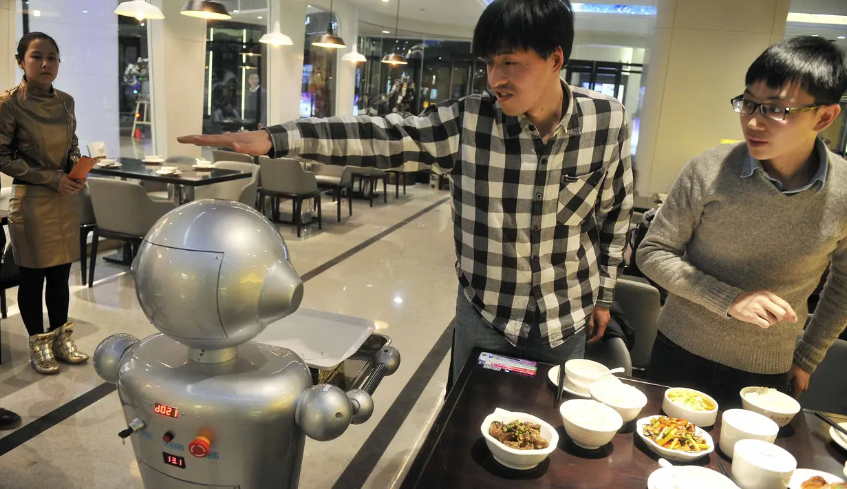 Seorang pria memberikan isyarat ke salah satu robot di restoran robot di Hefei, China, Jumat (26/12/2014). (REUTERS/Stringer)
