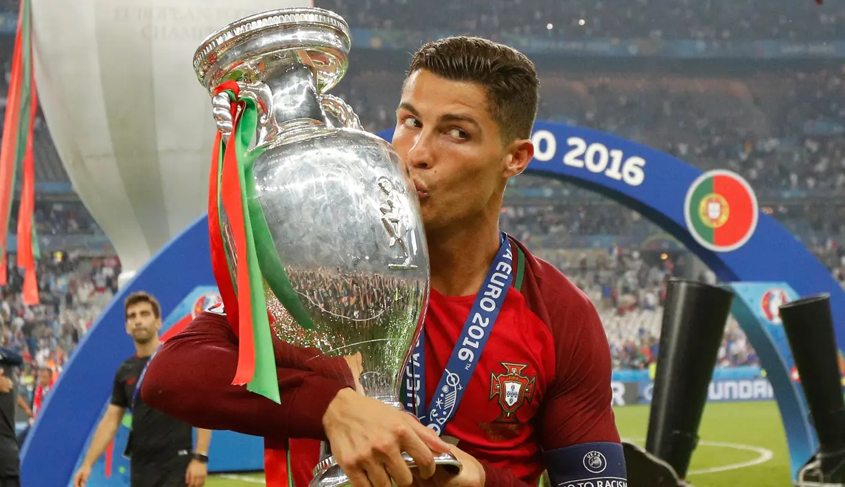 Cristiano Ronaldo menciumi Piala Eropa 2016 usai memenangkan laga melawan Prancis di Stade de France, Senin (11/7). Portugal menang dengan skor tipis 1-0. (REUTERS)