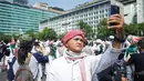 Anggota Laskar Front Pembela Islam (FPI) berswafoto saat melakukan konvoi melintas di kawasan Bundaran HI, Jakarta, Rabu (22/5/2019). Massa aksi 22 Mei akan mulai memadati sekitar Bawaslu selepas Dzuhur. (Liputan6.com/Immanuel Antonius)