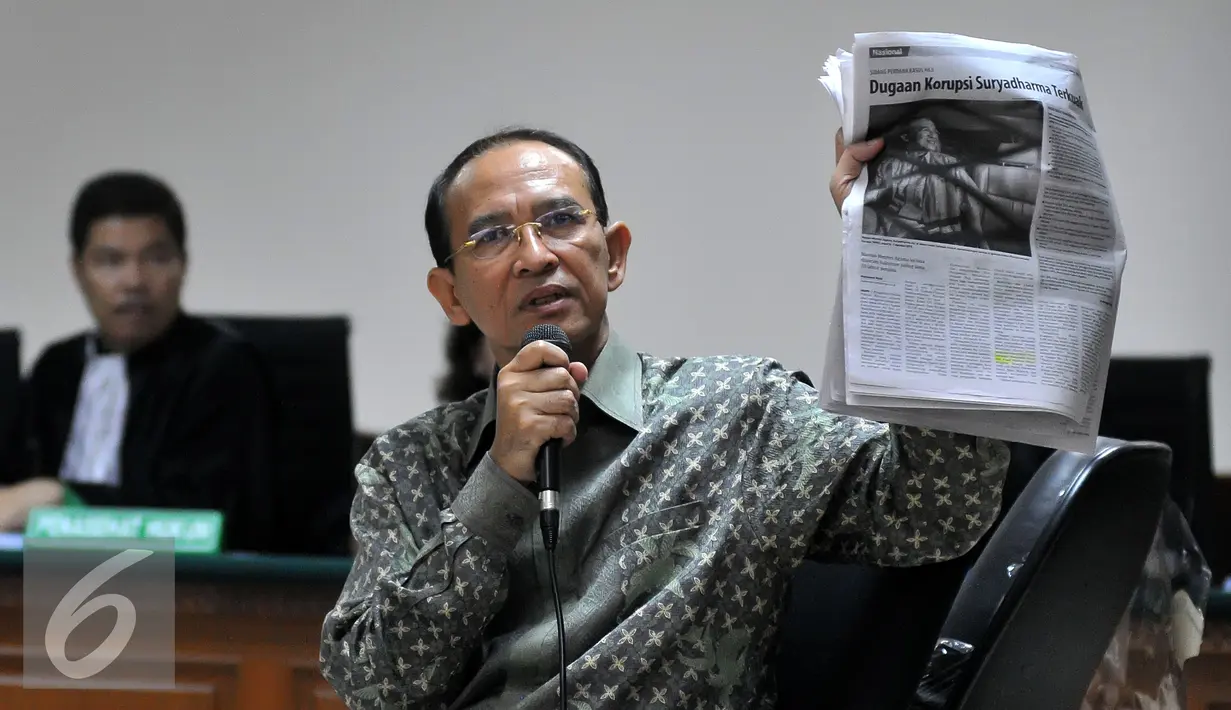 Suryadharma Ali (SDA) menunjukkan sebuah koran saat menjalani sidang pembacaan dakwaan di Pengadilan Tipikor, Jakarta, Senin (31/8/2015). SDA didakwa telah menggunakan Dana Operasional Menteri (DOM) hingga Rp1,821 miliar. (Liputan6.com/Herman Zakharia)