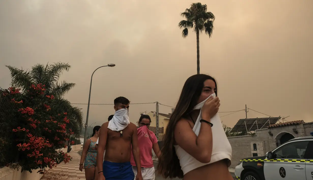 <p>Warga melindungi diri dari asap saat api menjalar di dekat area perumahan di Alhaurin de la Torre, Malaga, Spanyol, Sabtu (16/7/2022). Kebakaran hutan terus menyebar ke seluruh Spanyol ketika petugas pemadam kebakaran bekerja untuk mengendalikan api. (AP Photo/Gregorio Marrero)</p>