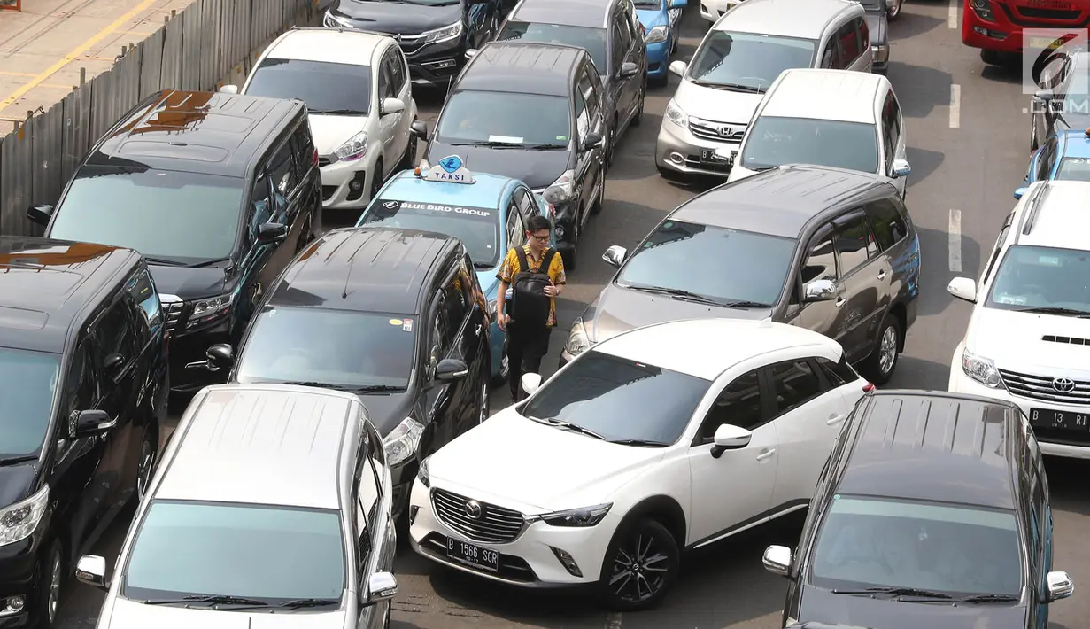 Seorang pejalan kaki melintas di kemacetan yang terjadi di kawasan Bundaran HI, Jakarta, Rabu (6/9). Kemacetan parah terjadi akibat ribuan massa aksi yang menutup jalan saat unjuk rasa di kantor Kedubes Myanmar. (Liputan6.com/Immanuel Antonius)