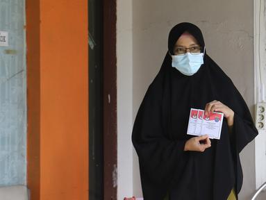 Warga yang diduga terpapar COVID-19 menunjukkan surat suara di kawasan Depok, Jawa Barat, Rabu (9/12/2020). Petugas KPPS melakukan jemput bola atau mengambil suara dari warga yang diduga terpapar COVID-19 atau sedang menjalani isolasi mandiri di Pilkada Depok 2020. (Liputan6.com/Herman Zakharia)