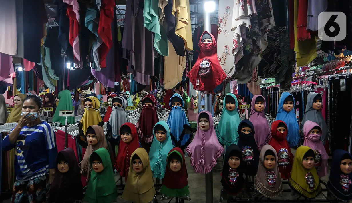 Seorang perempuan melintas di depan penjual gamis dan baju anak di pasar Parung, Bogor, Jawa Barat, Kamis (18/2/2021). Dampak pandemi COVID-19 yang berkepanjangan pedagang mengaku omset penjualan gamis dan baju anak turun 85 persen semenjak awal tahun lalu hingga sekarang. (Liputan6.com/Johan Tallo)