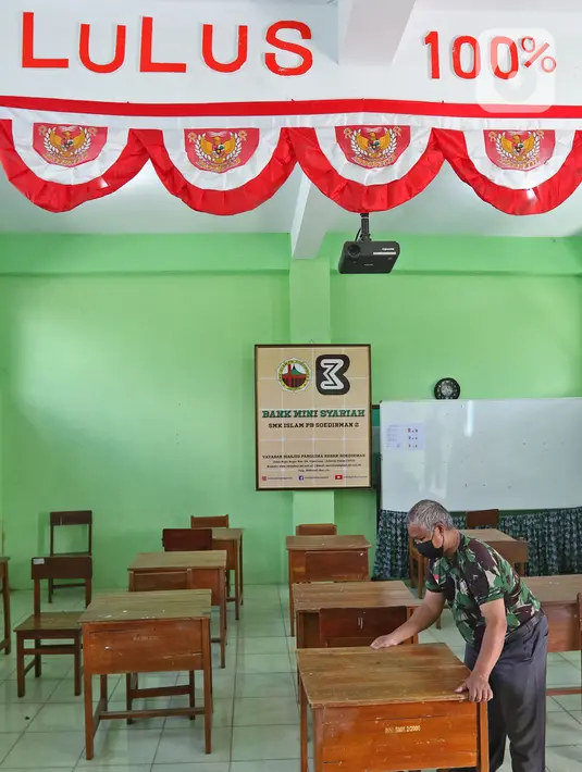 Petugas merapikan meja dan kursi jelang dibukanya pembelajaran tatap muka di SMK PB Soedirman 2, Jakarta, Selasa (6/4/2021). Pemprov DKI Jakarta akan melakukan uji coba pembelajaran tatap muka di 100 sekolah mulai 7 April hingga 29 April 2021. (Liputan6.com/Herman Zakharia)