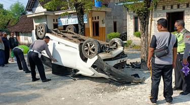 Kondisi mobil Xenia terbalik dan anggota Satlantas Polres Tuban ketika olah tempat kejadian perkara. (Ahmad Adirin/Liputan6.com)