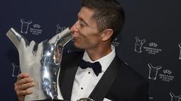 Penyerang Bayern Munchen, Robert Lewandowski mencium penghargaan Pemain Terbaik UEFA dalam acara UEFA Awards di Genewa, Swiss (1/10/2020). Lewandowski meraih penghargaan ini berkat penampilannya mengantarkan Munchen memenangi Liga Champions dan meraih treble.  (ROBERT HRADIL / AFP / UEFA)