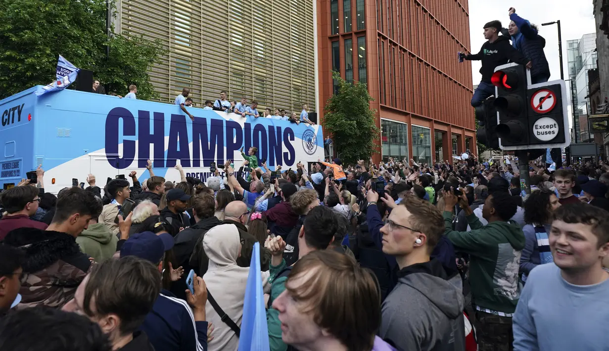 Para pemain Manchester City menyapa para penggemar dari atas bus saat parade kemenangan Liga Inggris di Manchester, Inggris, 23 Mei 2022. (AP Photo/Jon Super)