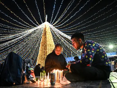 Keluarga-keluarga menyalakan lilin pada Hari Lilin Kecil ('Dia de las velitas'), di Bogota pada tanggal 7 Desember 2023. (Juan BARRETO/AFP)