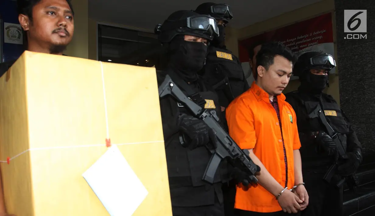 Tersangka pembunuh satu keluarga di Bekasi Haris Simamora (dua kanan) mendapat pengawalan polisi bersenjata di Polda Metro Jaya, Jakarta, Kamis (21/2). Selain Haris, polisi juga akan menyerahkan barang bukti dalam kasus ini. (Merdeka.com/Imam Buhori)