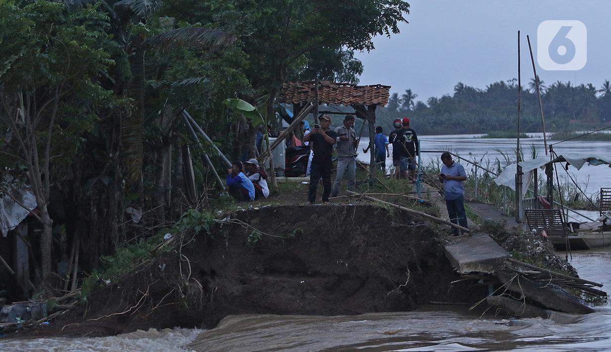 Warga berdiri di dekat banjir akibat tanggul jebol di Desa Sumberurip Pebayuran, Kabupaten Bekasi, Jawa Barat, Senin (22/2/2021). Banjir akibat luapan sungai Citarum mengakibatkan 5 Desa terisolir selama tiga hari akibat tanggul sungai Citarum jebol. (Liputan6.com/Herman Zakharia)