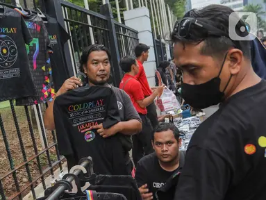 Pedagang menawarkan pernak pernik bergambar grup musik Coldplay di kawasan Senayan, Jakarta, Rabu (15/11/2023). (Liputan6.com/Angga Yuniar)