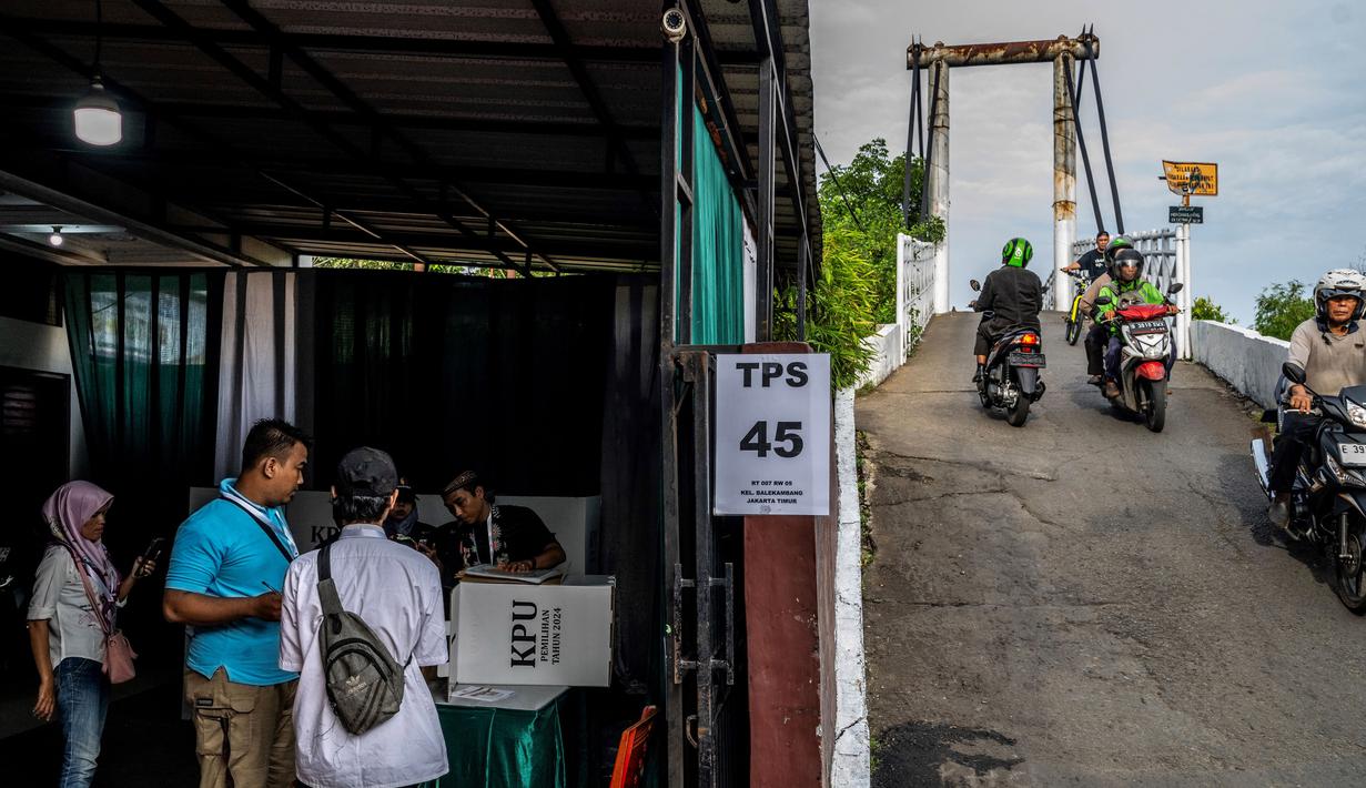 Pilkada 2024 menjadi momen bagi masyarakat Indonesia untuk menentukan pemimpin di daerahnya masing-masing. Tampak dalam foto, orang-orang melewati sebuah tempat pemungutan suara (TPS) dalam pilkada serentak di Jakarta pada 27 November 2024. (BAY ISMOYO/AFP)