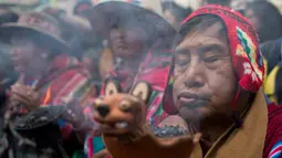 Anggota komunitas Andes membawa guci dengan dupa yang terbakar dalam sebuah arak-arakan patung dewa Ekeko di La Paz, Bolivia (23/1). Porsesi ini merupakan bagian dari acara pameran miniatur Alasita. (AP Photo / Juan Karita)