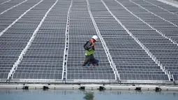 Petugas memeriksa panel surya fotovoltaik mengapung di kompleks pembangkit listrik O'Mega1 di Piolenc, Prancis selatan (30/7/2019). Pembangkit listrik tenaga surya (PLTS) mengapung pertama di Eropa ini akan beroperasi pada September 2019. (AFP Photo/Gerard Julien)