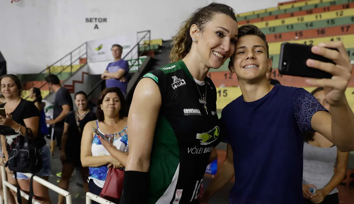 Seorang fans berselfie dengan Tiffany Abreu usai pertandingan liga voli Brasil di Bauru, Brasil,(19/12). Abreu, seorang transgender, mendapat otorisasi untuk bermain di liga voli wanita teratas negara tersebut. (AP Photo / Andre Penner)