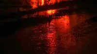 Asap dan api terlihat dari kejauhan setelah sebuah tangki minyak milik Pertamina, sebuah perusahaan minyak dan gas bumi milik negara, terbakar tanpa sebab yang jelas di Cilacap, Jawa Tengah (13/11/2021). (AFP/Dida Nuswantara)