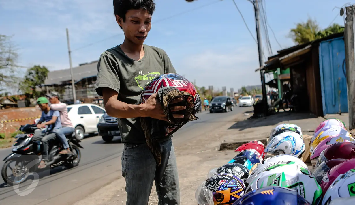 Pedagang sedang membersihkan helm dagangannya di kawasan Kali Malang, Jakarta, Selasa (14/7/2015). Meskipun mendekati hari lebaran mereka tetap berjualan aksesoris. (Liputan6.com/Faizal Fanani)