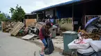 Seorang wanita memeluk anak di dekat puing-puing dan barang-barang di luar rumah mereka, setelah banjir surut di Mentakab, negara bagian Pahang Malaysia (11/1/2021). Banjir yang melanda daerah tersebut, membuat  Puluhan ribu warga dievakuasi. (AFP/Mohd Rasfan)