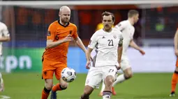 Gelandang Belanda, Davy Klaassen (kiri) berebut bola dengan gelandang Latvia, Kriss Karklins dalam laga Kualifikasi Piala Dunia 2022 Zona Eropa Grup G di Johan Cruijff Arena, Amsterdam, Sabtu (27/3/2021). Belanda menang 2-0 atas Latvia. (AFP/Maurice van Steen/ANP)