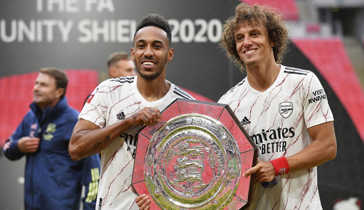 Pemain Arsenal, Pierre-Emerick Aubame dan David Luiz, mengangkat trofi Community Shield 2020 usai mengalahkan Liverpool di Stadion Wembley, Sabtu (29/8/2020) malam WIB. Arsenal menang 5-4 atas Liverpool lewat adu penalti. (Justin Tallis/Pool via AP)