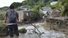Seorang pria menyaksikan tim penyelamat melanjutkan operasi pencarian di lokasi tanah longsor di Izusan di Atami, prefektur Shizuoka, barat daya Tokyo,  Senin (5/7/2021). Evakuasi korban hilang terus dilakukan menyusul bencana tanah longsor akibat hujan lebat di kota tersebut. (Kyodo News via AP)