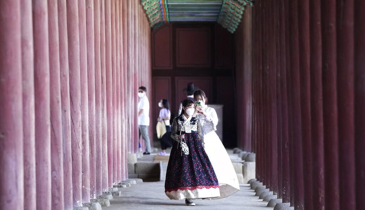 Seorang wanita mengenakan masker sebagai tindakan pencegahan terhadap virus corona mengambil foto temannya saat mereka mengunjungi Istana Gyeongbok untuk merayakan liburan Chuseok, Hari Thanksgiving versi Korea, di Seoul, Korea Selatan, Rabu (22/9/2021). ( AP Photo/Ahn Young-joon)
