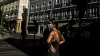 Seorang wanita yang mengenakan masker berdiri di depan alun-alun Camoes di Lisbon (14/7/2021). Hampir setengah dari populasi Portugal diberlakukan jam malam lagi awal bulan ini. (AFP/Patricia De Melo Moreira)