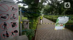 Petugas kebersihan sedang membersihkan didalam pembatas tulisan tanda ditutup sementara untuk mencegah penyebaran virus Covid-19 di Taman Suropati, Menteng, Jakarta, Senin (21/12/2020). (merdeka.com/Dwi Narwoko)