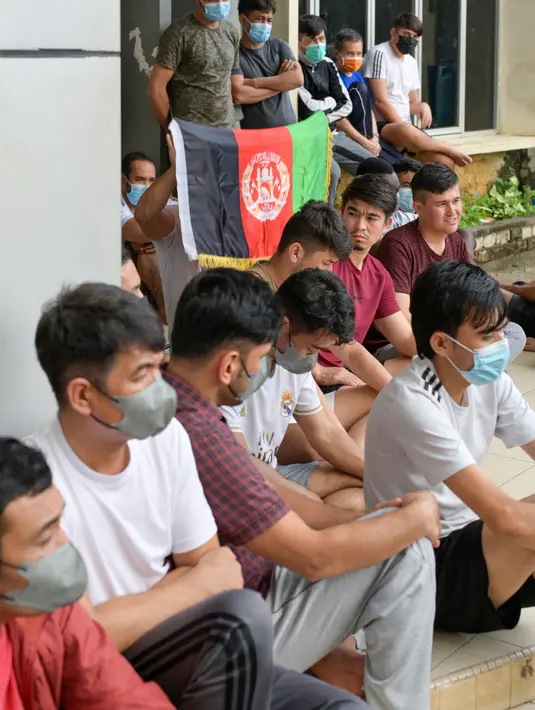 Pengungsi Afghanistan mengibarkan bendera negaranya untuk menunjukkan identitasnya di sebuah kamp pengungsi di Bekasi, Jawa Barat (20/8/2021). Mereka tidak bersedia kembali ke negaranya, terutama setelah Taliban mengambil alih kekuasaan dari pemerintahan Presiden Ashraf Ghani. (AFP/Bay Ismoyo)