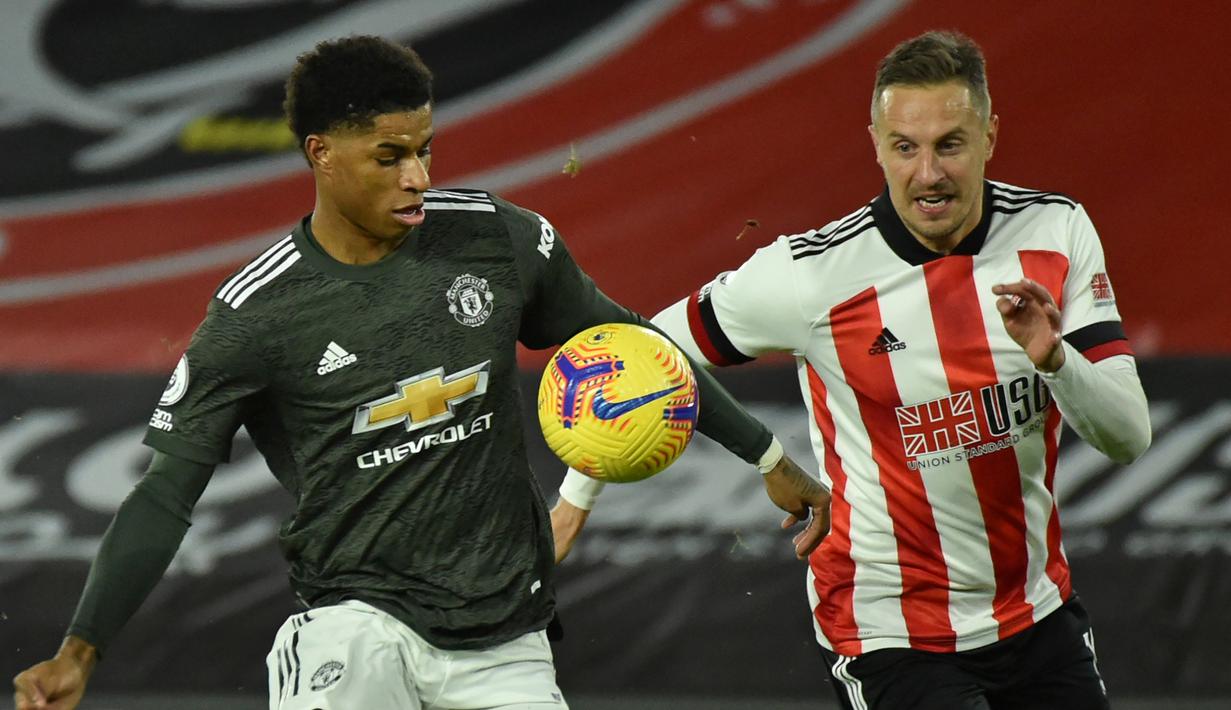 Striker Manchester United, Marcus Rashford (kiri), berebut bola dengan bek Sheffield United, Phil Jagielka, dalam laga lanjutan Liga Inggris 2020/21 pekan ke-13 di Bramall Lane, Sheffield, Kamis (17/12/2020). Manchester United menang 3-2 atas Sheffield United. (AFP/Rui Vieira/Pool)