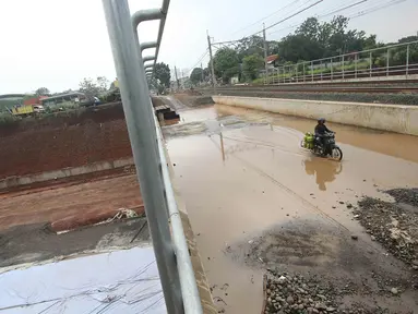 Pengendara motor melintasi genangan air di kawasan Kemiri Muka, Depok, Jawa Barat, Senin (2/10). Buruknya sistem drainase menyebabkan air selalu menggenang setiap musim hujan sehingga mengganggu aktivitas warga. (Liputan6.com/Immanuel Antonius)