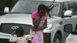 Seorang gadis muda menutupi wajahnya dari angin dan hujan yang dihasilkan oleh Badai Ida di New Orleans, Minggu (29/8/2021).  Badai level 4 itu memanjang hingga sejauh 50 mil dari episentrumnya. (AP Photo/Eric Gay)