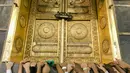 Umat muslim memagang pintu Kakbah di Masjidil Haram, Mekah, Arab Saudi, Jumat (17/8). Kakbah menjadi kiblat umat muslim seluruh dunia saat melaksanakan salat. (AP Photo/ Dar Yasin)