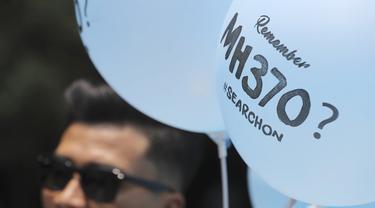 Seorang relawan membagikan balon bergambar MH370 pada acara Day of Remembrance MH370 di Kuala Lumpur, Malaysia, Minggu, 3 Maret 2019. (Foto AP/Vincent Thian)