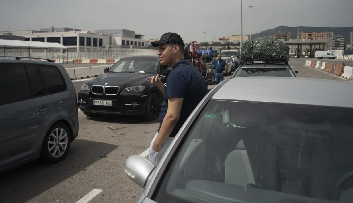 Seorang penumpang berbicara di telepon saat mereka menunggu untuk naik feri menuju Tangier di pelabuhan Algeciras, Spanyol, Rabu (15/6/2022). Ribuan warga negara Maroko yang bekerja dan tinggal di Eropa melewati Selat Gibraltar saat mereka kembali untuk menghabiskan liburan musim panas di Maroko. (JORGE GUERRERO / AFP)