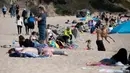 Orang-orang menikmati hari yang cerah di pantai Sa Conca di Castell-Platja D'Aro dekat Girona, Spanyol pada Rabu (31/3/2021). Spanyol termasuk negara yang parah terhantam pandemi covid-19 dengan lebih dari 75 ribu kematian dari hampir 3,3 juta kasus. (Josep LAGO / AFP)