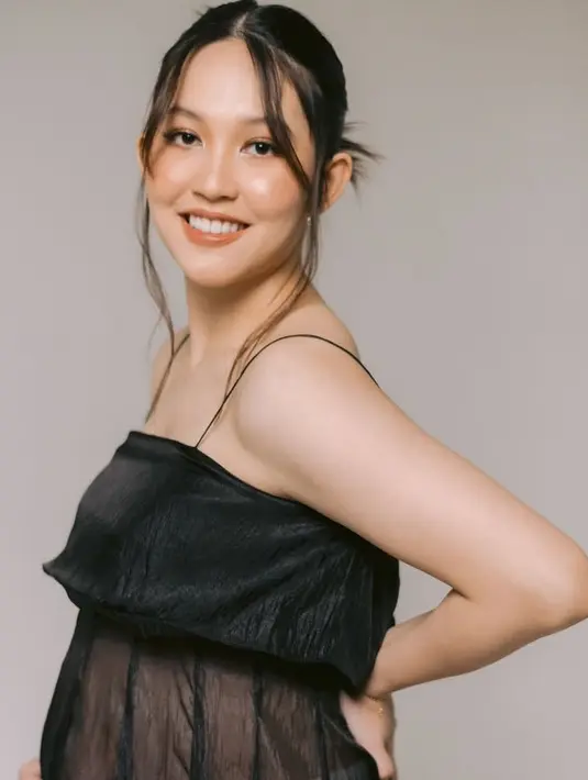 Wajahnya dipulas makeup warm dengan blush on coral kecoklatan, senada dengan lipstik glossynya. Rambutnya ditata ikat belakang dengan poni depan panjang. [@venemapictures]