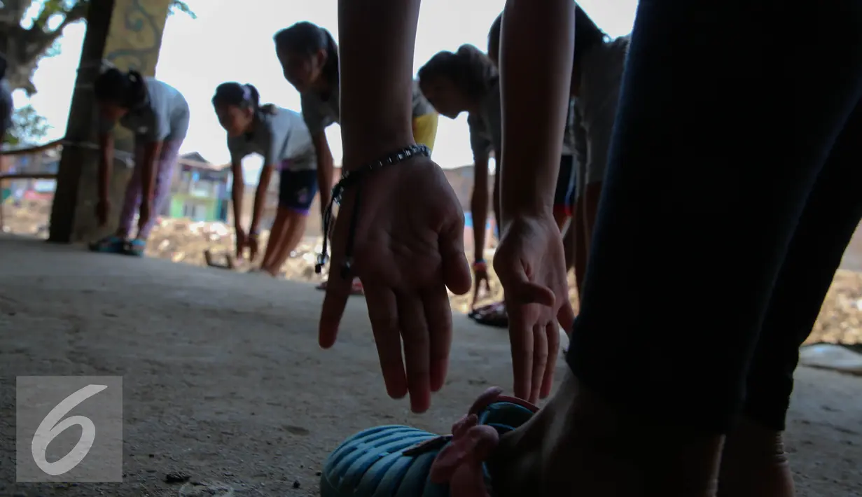 Sejumlah anak melakukan gerakan pemanasan saat berlatih balet di Bantaran Kali Ciliwung, Jakarta, Sabtu (29/8/2015). Pelatihan ini adalah kerjasama antara Kedubes Australia dengan Yayasan Bina Ballet Indonesia. (Liputan6.com/Faizal Fanani)