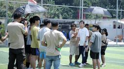 Sejumlah kru sedang melakukan briefing bersama mantan pelatih Timnas Indonesia, Shin Tae-yong saat melakukan syuting film Ghost Soccer: Bola Mati yang berlangsung di Cisalak, Subang, Jawa Barat pada Minggu (19/01/2025). (Bola.com/Rivo Falah Naufal)