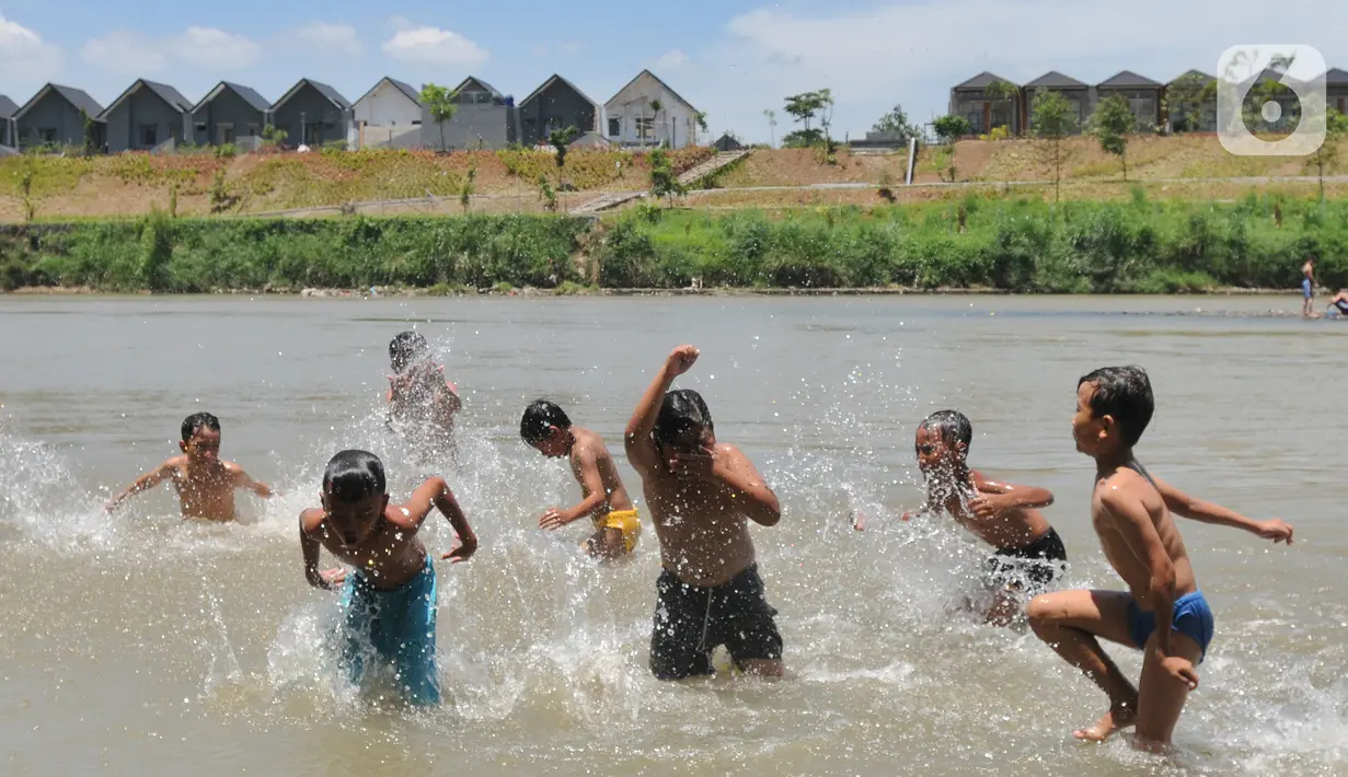 Anak-anak bermain pada aliran Sungai Cisadane di kawasan Keranggan, Setu, Tangerang Selatan, Banten, Minggu (20/3/2022). Cuaca panas terik dimanfaatkan mereka untuk berendam sambil bermain. (merdeka.com/Arie Basuki)