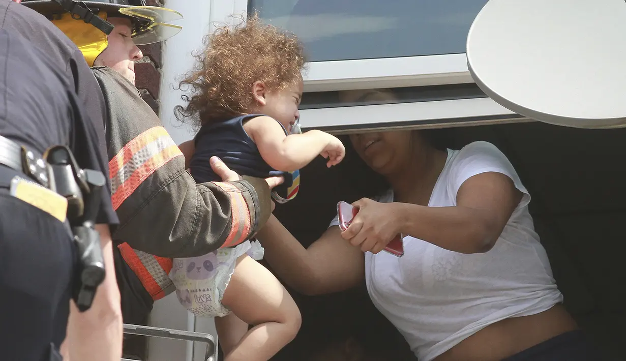 Petugas pemadam kebakaran menyalamatkan bayi setelah kebakaran terjadi di dalam gedung di Hazleton, Pennsylvania (26/7/2019). Restoran dan apartemen Prestigio rusak dilalap api. (Warren Ruda/Hazleton Standard-Speaker via AP)
