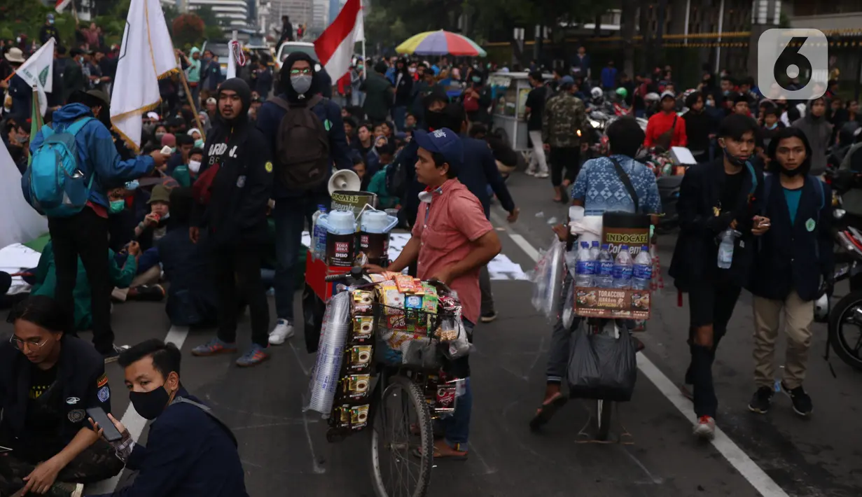 Pedangang menawarkan dagangannya kepada massa aksi saat demo penolakan omnibus law di kawasan patung kuda, Jakarta, Selasa (20/10/2020). Para pedagang kaki lima memanfaatkan moment aksi massa untuk mencari ke untungan meskupun sangat membahayakan bagi keselamatan mereka. (Liputan6.com/Angga Yuniar)