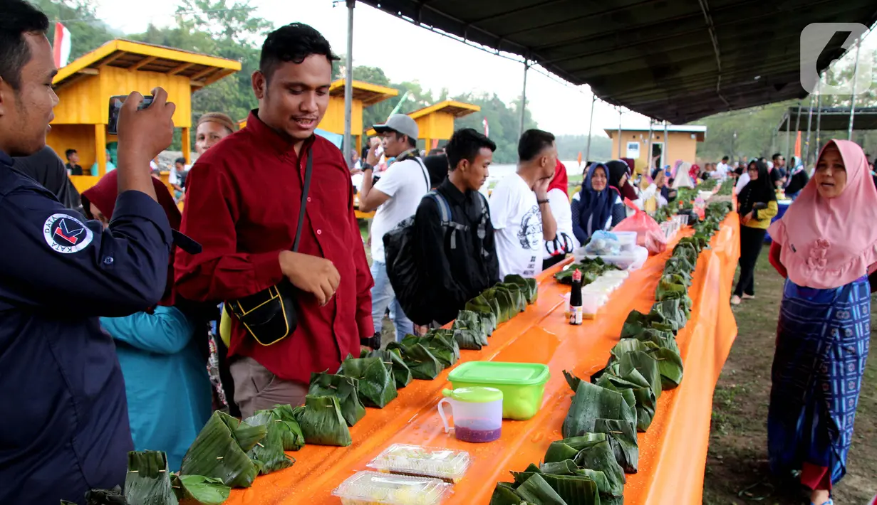 Warga melihat bungkus nasi kuning selama Gebyar Safar 1441 H di Desa Pangi, Kecamatan Suwawa Timur, Kabupaten Bone Bolango (Bonebol), Rabu (23/10/2019). “Nasi kuning itu melambangkan leluhur kita,” ujar Kepala Desa Pangi, Saprin Suleman. (Liputan6.com/Arfandi Ibrahim)