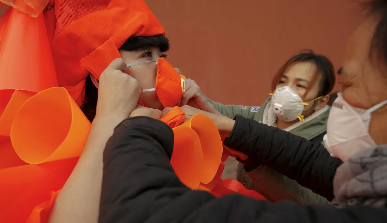 Kong Ning saat dibantu rekannya memakai kostum berwarna oranye yang terbuat dari plastik untuk aksi protesnya di Beijing, Cina, (7/12). Ini merupakan bagian protes terhadap polusi udara yang semakin parah di Cina. (REUTERS/Damir Sagolj)