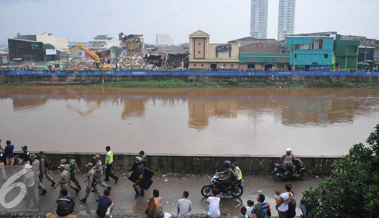 Warga menyaksikan pembokaran bangunan di kawasan prostitusi Kalijodo, Jakarta Utara, Senin (29/2). Puluhan bangunan di kawasan tersebut mulai rata dengan tanah serta menjadi tontonan warga. (Liputan6.com/Gempur M Surya)