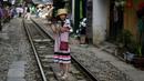 Foto pada 8 Juni 2019 memperlihatkan seorang wanita berswafoto di tengah jalur kereta api populer di Hanoi, Vietnam. Turis sengaja datang ke Old Quarter untuk berfoto di rel kereta api yang dianggap ' instagramable' tersebut. (Photo by Manan VATSYAYANA / AFP)