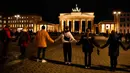 Warga membentuk rantai manusia saat berkabung untuk para korban penembakan brutal di Hanau di Gerbang Brandenburg Berlin, Jerman, Kamis (20/2/2020). Polisi masih menyelidiki keterlibatan orang lain dalam penembakan tersebut. (AP Photo/Markus Schreiber)
