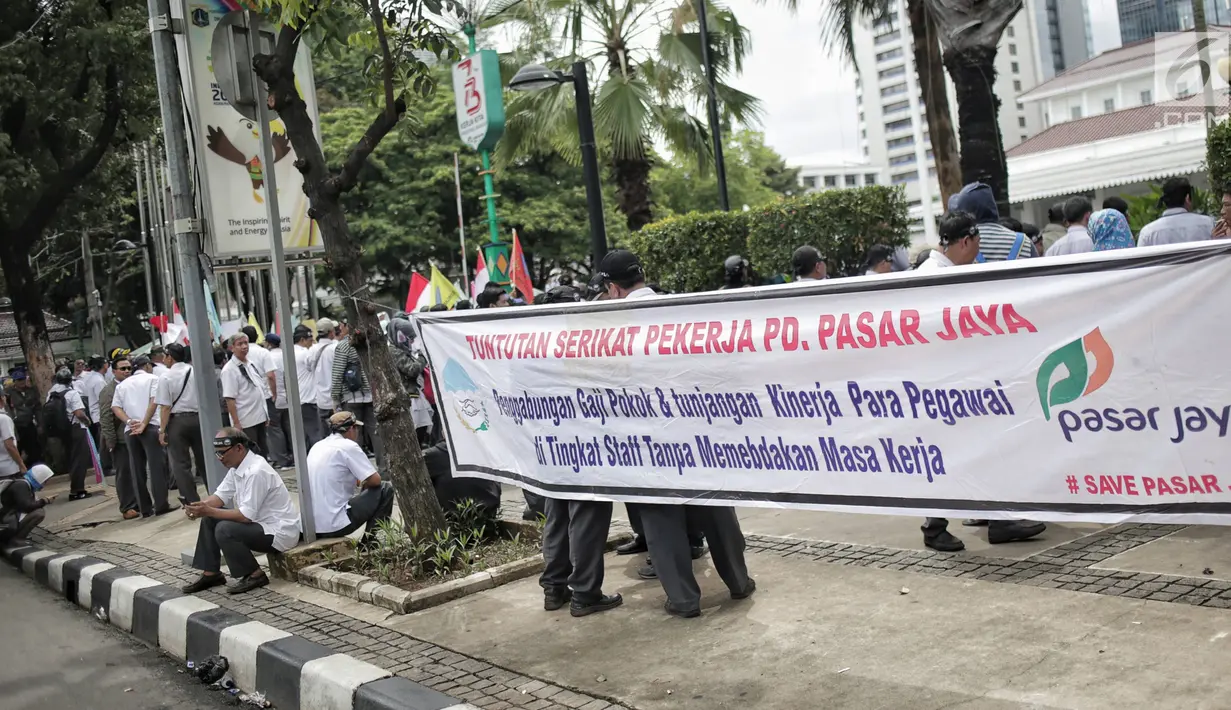 Massa dari SP PD Pasar Jaya membentangkan spanduk dalam unjuk rasa di Balai Kota DKI Jakarta, Rabu (31/1). Mereka menuntut untuk menghentikan rekrutmen tenaga profesional yang melanggar peraturan Pasar Jaya SK 65 Tahun 2016. (Liputan6.com/Faizal Fanani)
